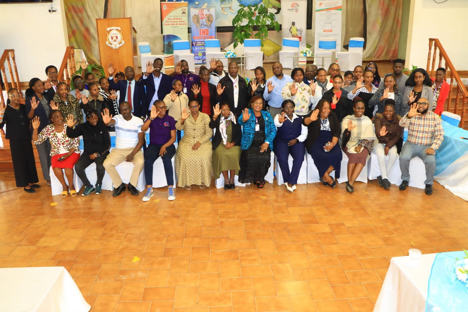 Conference participants raise their hands in a collective pledge to end human trafficking and modern slavery